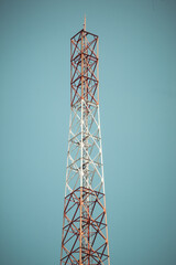 Telecommunication tower with multiple antennas and transmitters standing against a clear blue sky