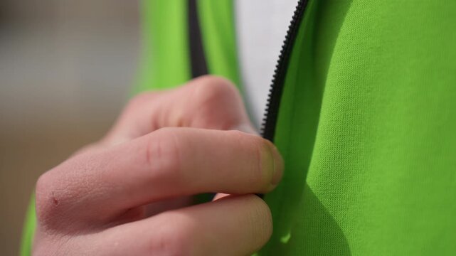 zipper ready outdoor, preparing for outdoor activity with zipped jacket, fingers pulling zipper on jacket in outdoor training, closeup of hands zipping green jacket during outdoor training preparation