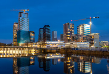 Skyline of Amsterdam Zuidoost, modern high-rise residential towers in final stages of development reflected in water