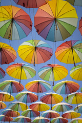 Many rainbow colored umbrellas against blue sky