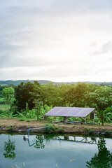 Solar water pump motor that is powered by grey black solar cell panel stands at the bank of the water pond for electric generating duty in fish farm at Thailand. Vertical.