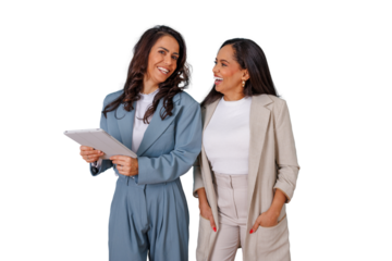 Two diverse businesswomen smiling and interacting, one holding a tablet, representing professional collaboration and female empowerment