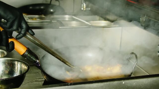 Cook stirs noodles while tiny flames lick the curved wok. Station handles rush orders for travelers and late night delivery in busy Vietnam city