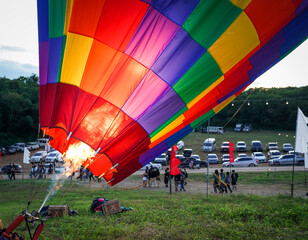 Man prepare massive colorful hot air balloons for liftoff in the sky display in festival.