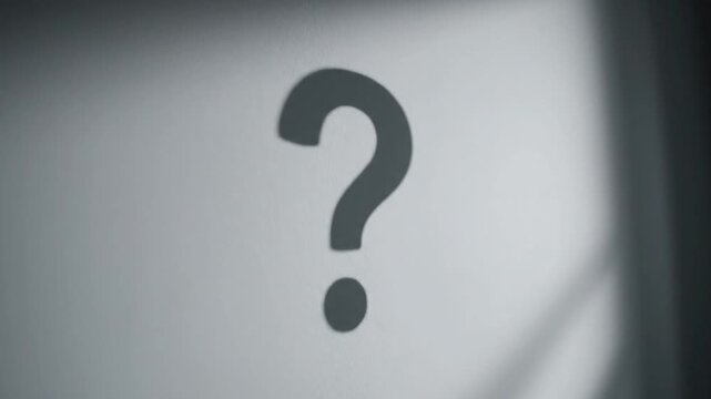 Question mark shadow on a textured wall symbolizing doubt