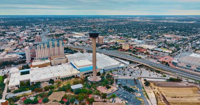 Flying around the Tower of Americas. View on the lively highway crossing the cityscape of San Antonio, Texas, USA. Drone footage on cloudy day.