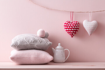 Heart shaped decor and pillows on a soft pink shelf.