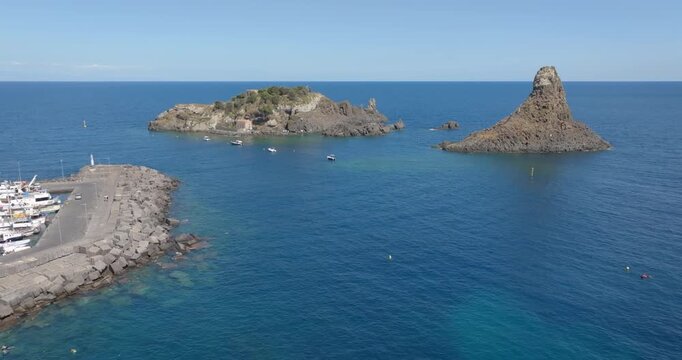 Aerial view of the Cyclopean Isles. These are small islands and basalt rocks located in the province of Catania, Sicily, Italy. In the background, on the horizon, is the Mediterranean Sea. Summer day.