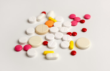 Colorful tablets and capsules on a light background. The concept of medical care. Pharmaceutical preparations for the treatment of sick patients. Close-up macro photography.