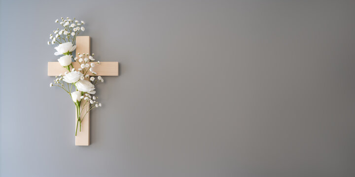 A simple wooden cross with fresh white flowers on a gray background. Christian symbol for Easter, Good Friday, or a funeral with copy space for text