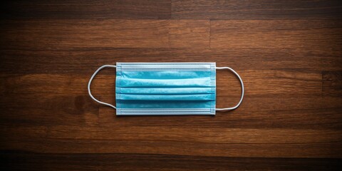 Single-use medical mask placed on a wooden background, highlighting infection control measures