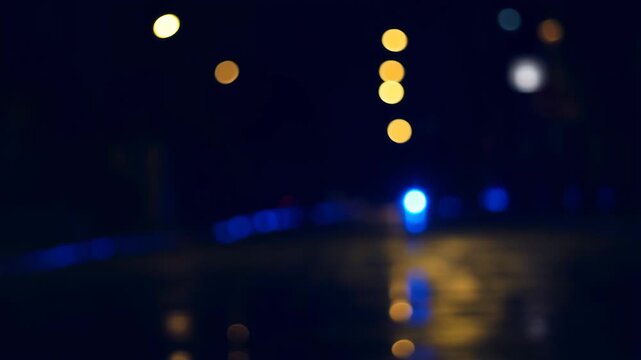 Blurry view of police lights reflecting on wet pavement at night. Emergency response scene highlighting public safety and law enforcement presence
