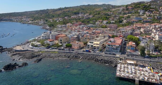 Aerial view of the Aci Trezza waterfront overlooking the Mediterranean Sea, in the province of Catania, Sicily, Italy. In the background is the center of the town. It's a sunny summer morning.
