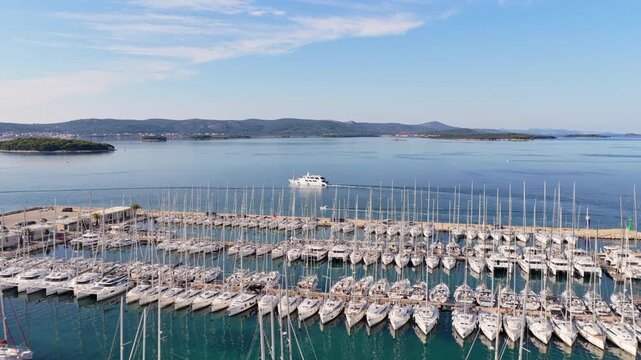 Aerial drone view of a large marina packed with boats and sailboats, with calm blue water and distant islands. Biograd na Moru, Croatia