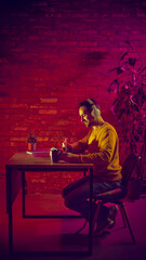 Professional working on digital tablet at desk under neon light. Concept of digital workspace, focused remote work, technology driven productivity, creative concentration, and modern work routine