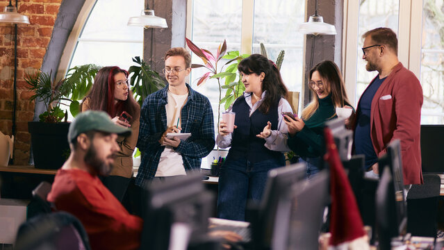 Coworking team casual discussion during work break in open office. Concept of modern workspace culture, employee engagement, informal communication in contemporary office environments. - Powered by Adobe
