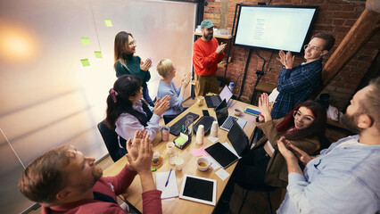 Team collaboration around table in modern coworking office. Concept of shared work process, cross functional teamwork, collaborative office culture.