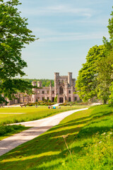 Obraz premium Lowther Castle, Cumbria. Historic castle ruins in green park with path, trees, and bright blue sky