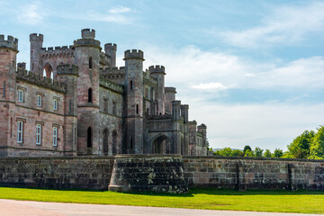 Lowther Castle, Cumbria. Historic stone castle with turrets and gatehouse standing over green lawns on a sunny day © Tommy Lee Walker