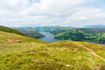 Ullswater, Lake District. Panoramic hilltop view over lake valley with rolling green fields and distant hills