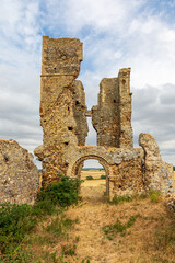Bawsey ruin, near King's Lynn, Norfolk. Ancient stone church tower ruins with archway in open countryside under blue sky