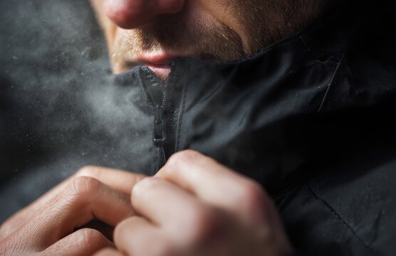 Close up of man zipping jacket with cold breath