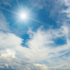 Atmospheric sky view with sunlight radiating outward and clouds drifting across open space in vibrant daylight
