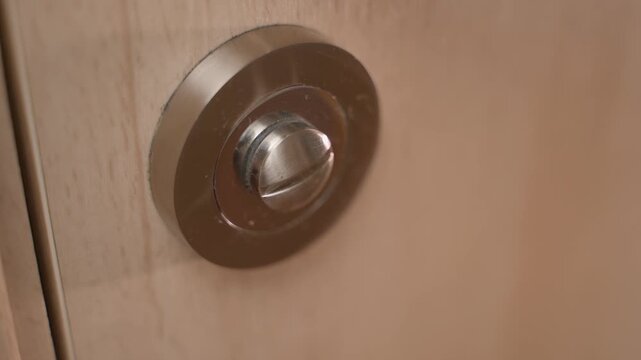 A person enters the toilet and closes the lock, close-up. Closing and opening the interior lock in the door