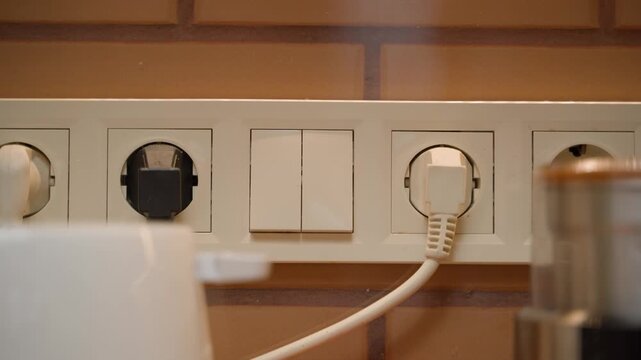 Turning the light on and off in the kitchen, close-up. Sockets and light switch in the wall