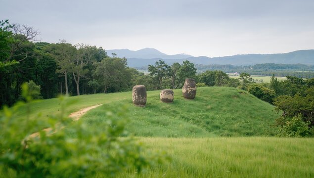 Archaeological site on a hillside surrounded by trees close to a village in Xieng Khouang Province, preservation efforts