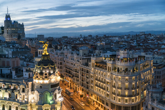 Aerial view of the Metropolis Building's golden statue gleaming against the twilight sky, with the Telef&oacute;nica Building standing tall in the distance, Madrid, Community of Madrid, Spain.