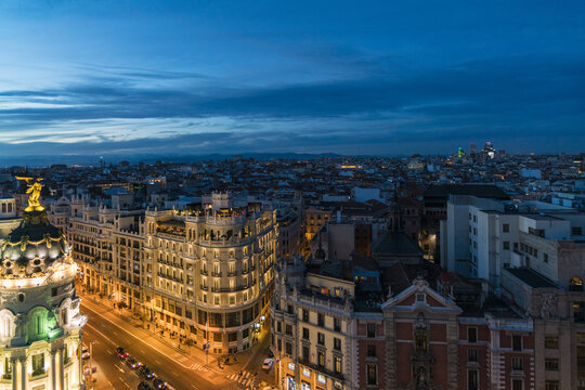 Aerial view of illuminated buildings and streets under a twilight sky reveals the beauty of cityscape, Madrid, Community of Madrid, Spain.
