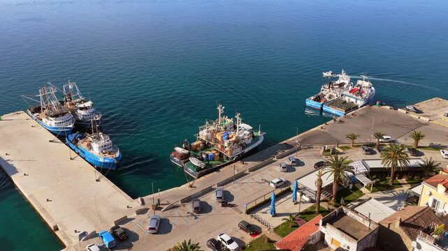 Aerial drone view of a concrete pier with several fishing vessels and workboats docked along the edge. Biograd na Moru, Croatia