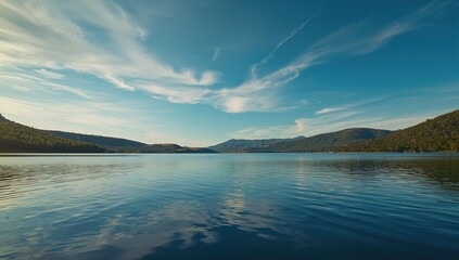 Obraz premium Wide-angle landscape of a lake under bright sunlight, highlighting scenic water and sky