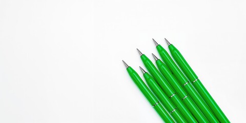 Set of green writing instruments on a plain white surface, ideal for editorial headers