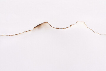 Burnt edge of white paper creating mountain silhouette with brown and black charred details.
