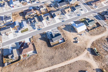 Aerial view of houses with contrasting roof colors interspersed with bare land patches and streets creates a textured tapestry of urban development, Buena Vista, Colorado, United States.