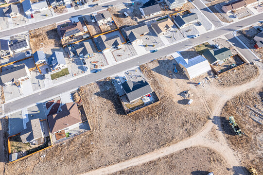Aerial view of houses with contrasting roof colors interspersed with bare land patches and streets creates a textured tapestry of urban development, Buena Vista, Colorado, United States.