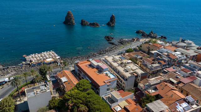 Aerial view of the waterfront of Aci Trezza, Sicily, Italy. Opposite the town are the Cyclopean Isles, a small archipelago formed as a result of intense volcanic activity. It is a sunny day morning.