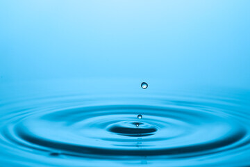 A captivating image of a water droplet creating ripples on a serene surface. The blue color creates a calming and refreshing ambiance. 