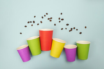 Top view showing assorted paper coffee cups and coffee beans on a blue backdrop, Top view. Flat lay.