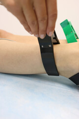 Patient&rsquo;s ankle prepared with electrode and green strap during medical examination.