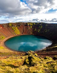 Deep azure lake in volcanic crater under cloudy skies