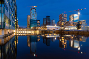 Modern high-rise residential towers in final construction phase reflecting in water, Amsterdam Zuidoost skyline, Netherlands