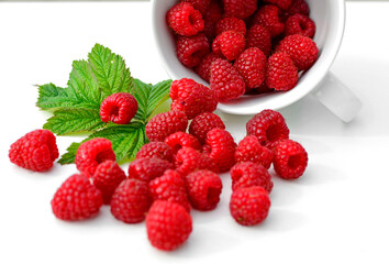 maliny w białym kubku, czerwone maliny, maliny z zielonym liściem, fresh raspberries in a cup, red raspberries, juicy raspberries with a green leaf, Rubus idaeus, rasberry view from above, białe tło © kateej