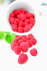 maliny w białym kubku, czerwone maliny, maliny z zielonym liściem, fresh raspberries in a cup, red raspberries, juicy raspberries with a green leaf, Rubus idaeus, rasberry view from above, białe tło