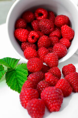 maliny w białym kubku, czerwone maliny, maliny z zielonym liściem, fresh raspberries in a cup, red raspberries, juicy raspberries with a green leaf, Rubus idaeus, rasberry view from above, białe tło © kateej
