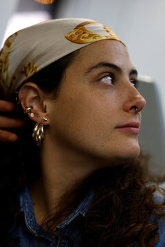Close up side view portrait of a caucasian adult woman in her 30s looking away indoors. Natural light, realistic skin texture and thoughtful expression. Concept of lifestyle, identity and modern femin