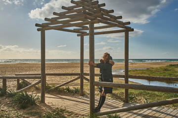 Woman enjoying winter sun on beach under pergola