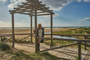 Woman standing in wooden pergola enjoying beach view